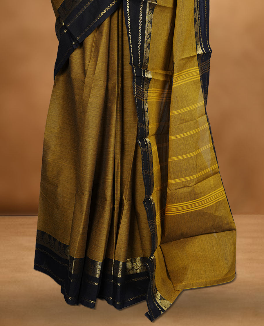 Dark mustard yellow colour chettinad cotton saree featuring plain body, paired with a black colour traditional gold zari border without blouse.