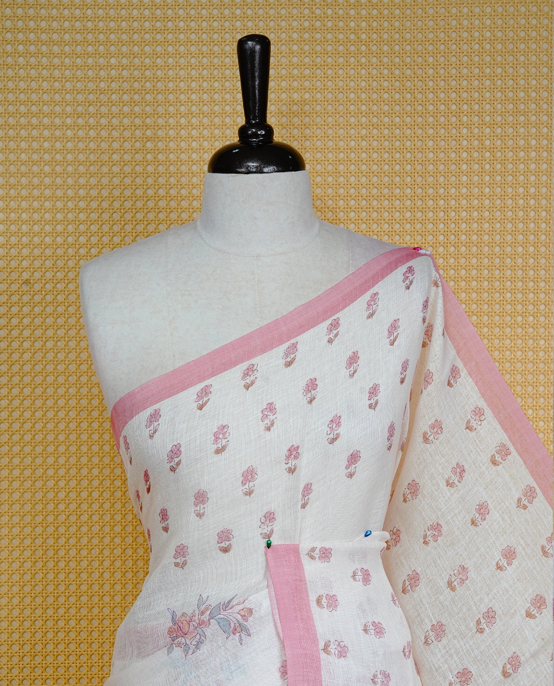 Cream colour semi linen saree featuring Floral printed buttas on body, complemented by contrast Peach colour border, comes with matching blouse piece.