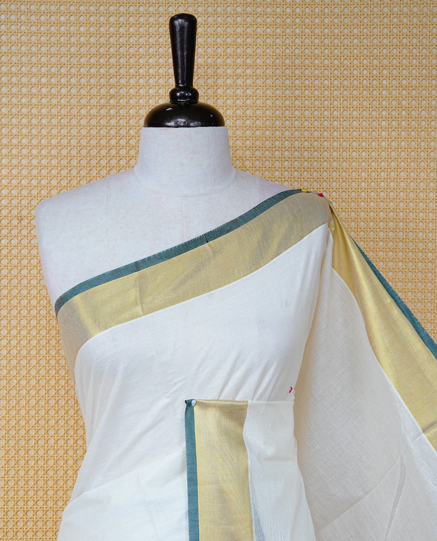 Cream Colour Cotton Kerala Saree Featuring A Plain Body, Enhanced With A Gold Zari & Green Colour Border, A Traditional Gold Zari Pallu, Green Tassels, And A Matching Blouse Piece.