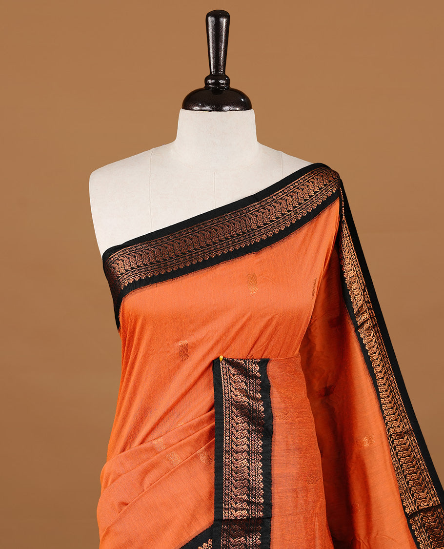 Orange colour kalyani cotton saree featuring gold zari motifs on body, highlighting contrast Black colour with Antique gold zari border, paired with matching blouse piece.