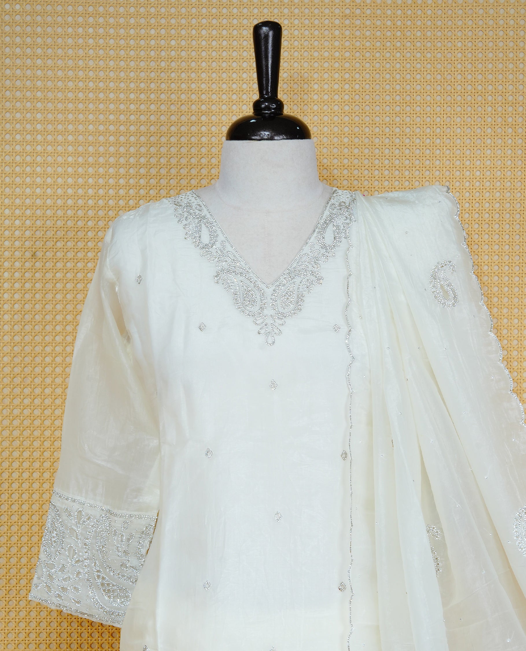 Off White colour churidar set featuring delicate Stone Work on the V-neckline, sleeves and hem, paired with matching solid pants and an embellished sheer dupatta.