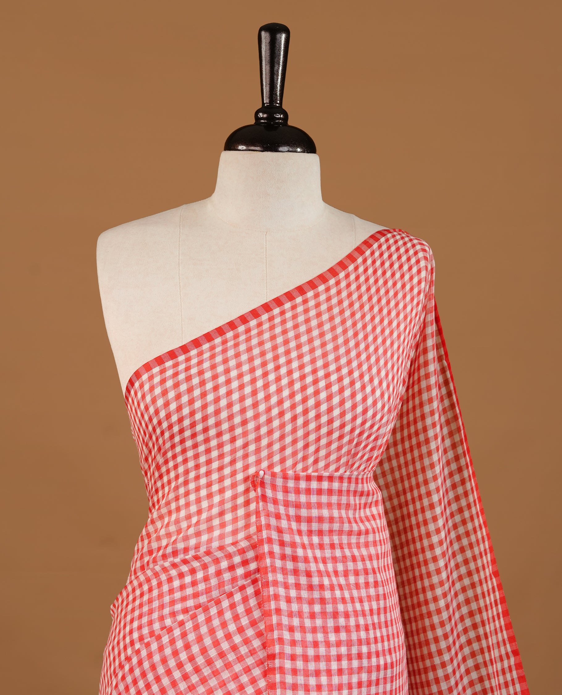 Red and White colour Mul Cotton saree featuring a classic small check pattern on the body, accented with tassels for added charm. Comes without a blouse piece.