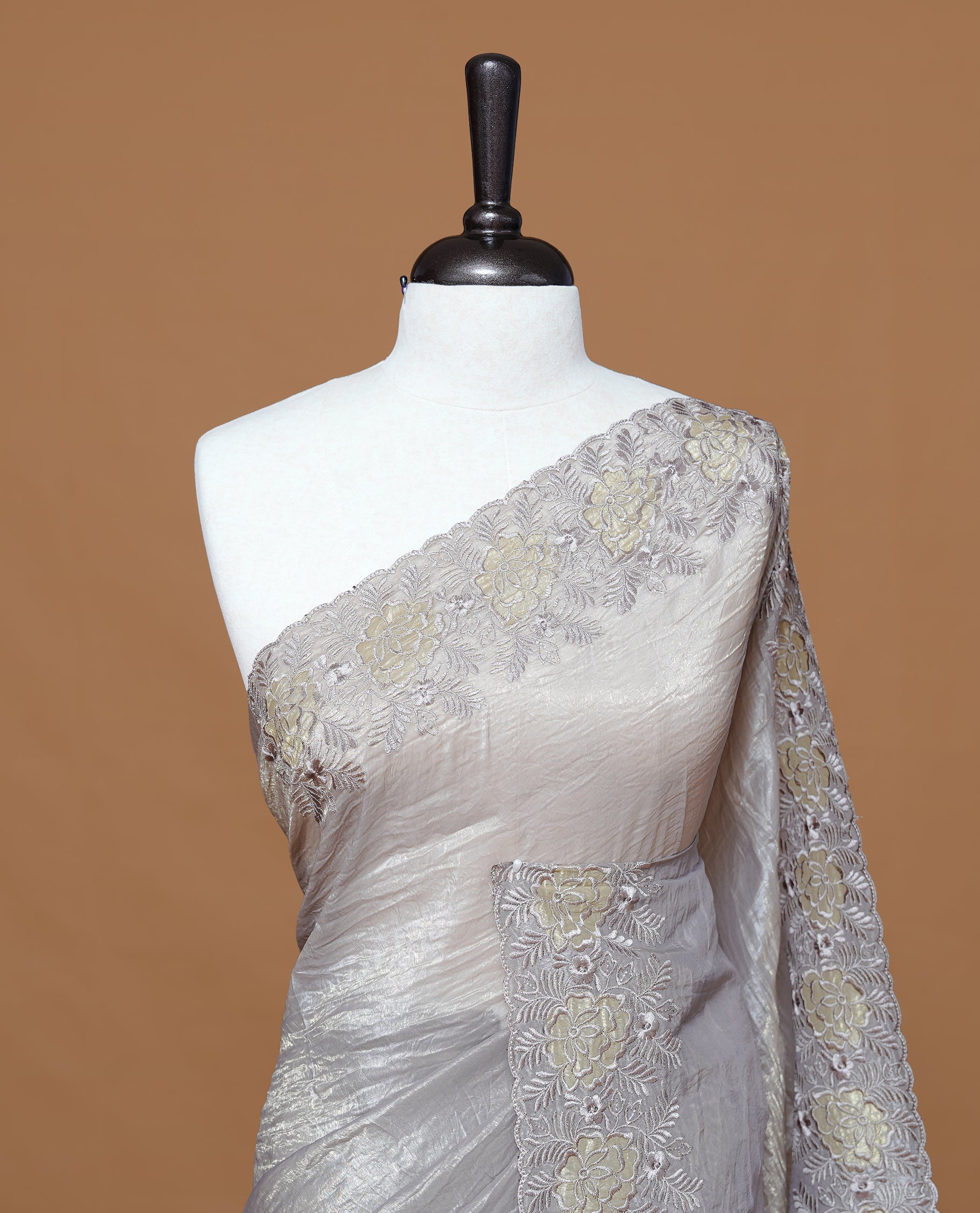Grey colour Crush Organza Featuring Plain body, Enrich with Floral thread pattern & scalp border, paired with matching blouse piece.