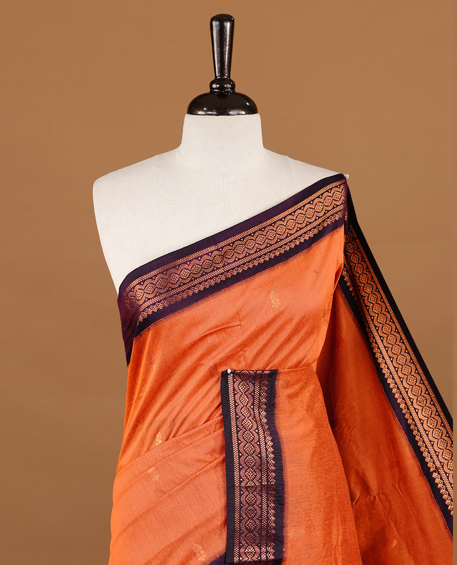 Orange colour kalyani cotton saree featuring gold zari motifs on body, highlighting contrast Purple colour with Antique gold zari border, paired with matching blouse piece.