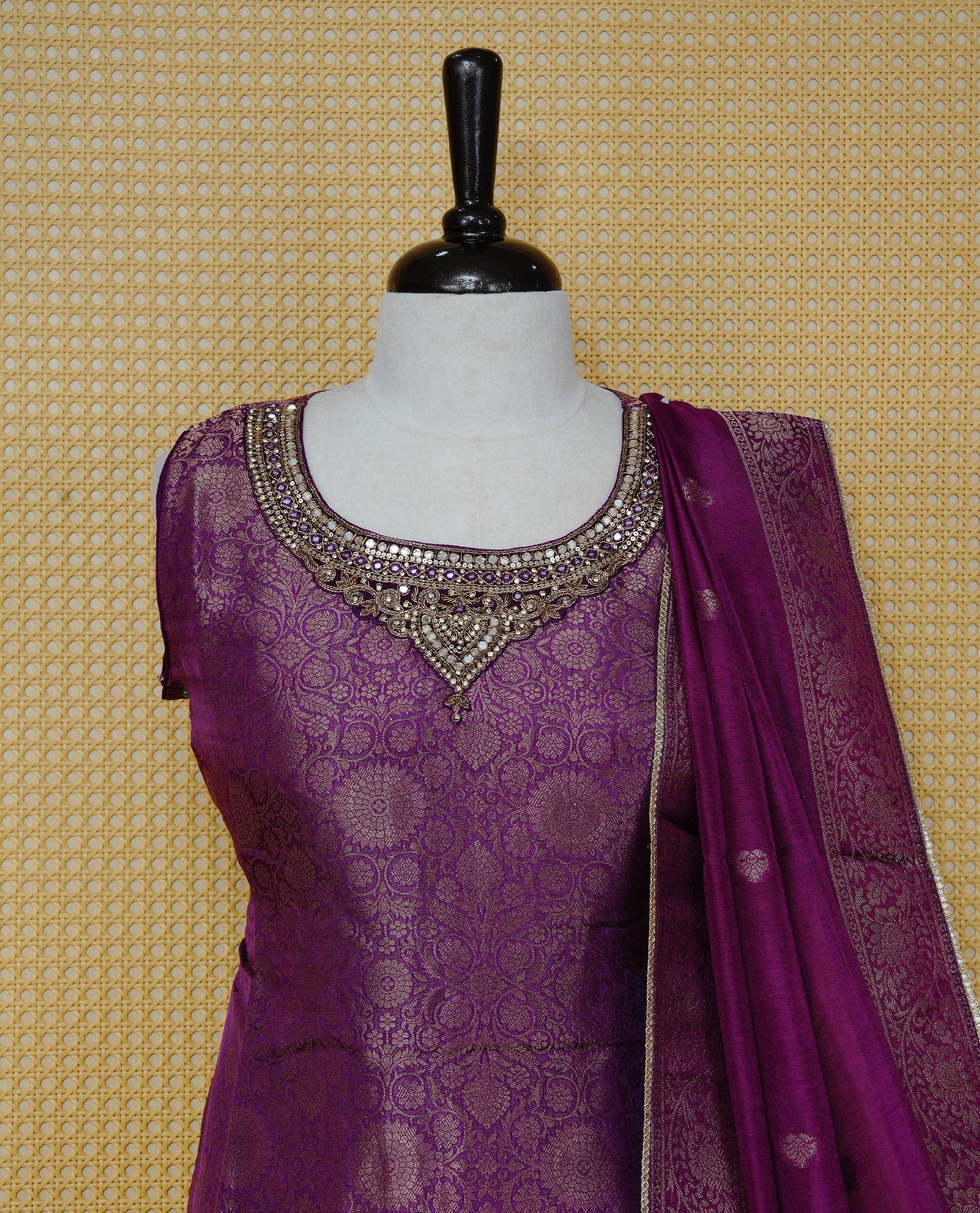 Royal purple churidar set with an ornate embellished round neckline, floral zari pattern, paired with a matching dupatta featuring zari butis and an intricate border & solid pants.