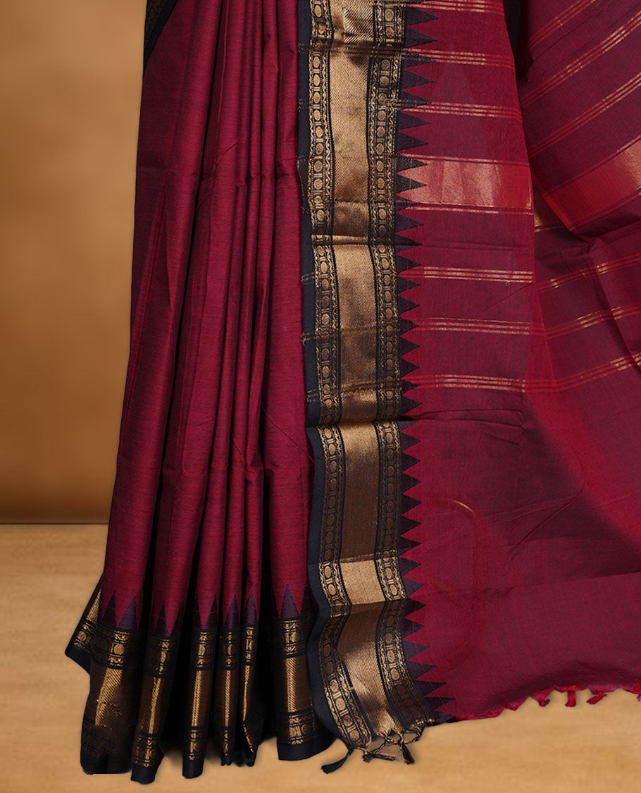 Deep red colour chettinad cotton saree featuring elegant plain body highlighting contrast black colour with gold zari traditional border, pallu and paired with matching blouse piece.