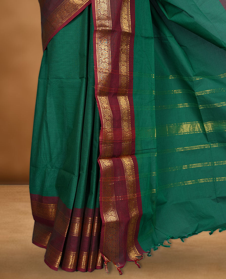 Dark green colour chettinad cotton saree featuring elegant plain body highlighting contrast maroon colour colour with gold zari traditional border, pallu and paired with matching blouse piece.