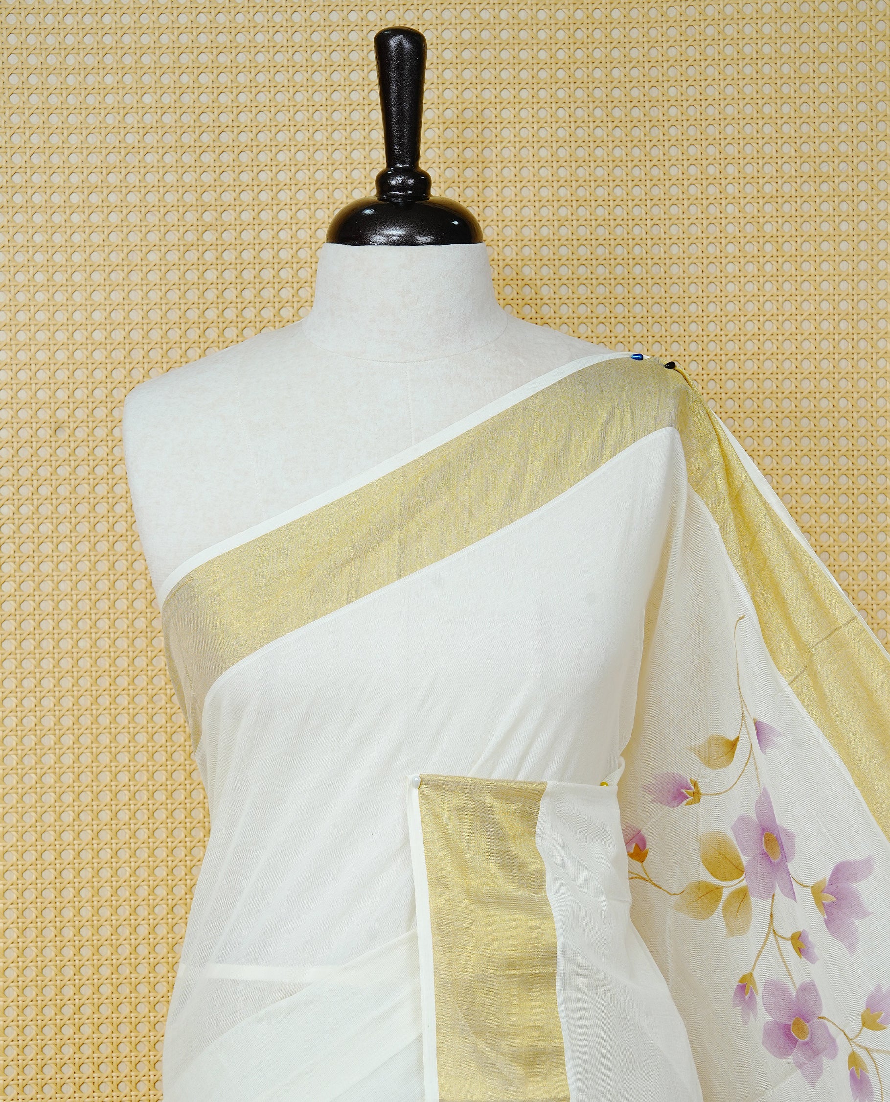 Cream Colour Cotton Kerala Saree Featuring Digital Purple Floral Prints Across The Body, Enhanced With A Gold Zari Border, Traditional Gold Zari Pallu, Finished With Purple & White Tassels And A Matching Blouse Piece