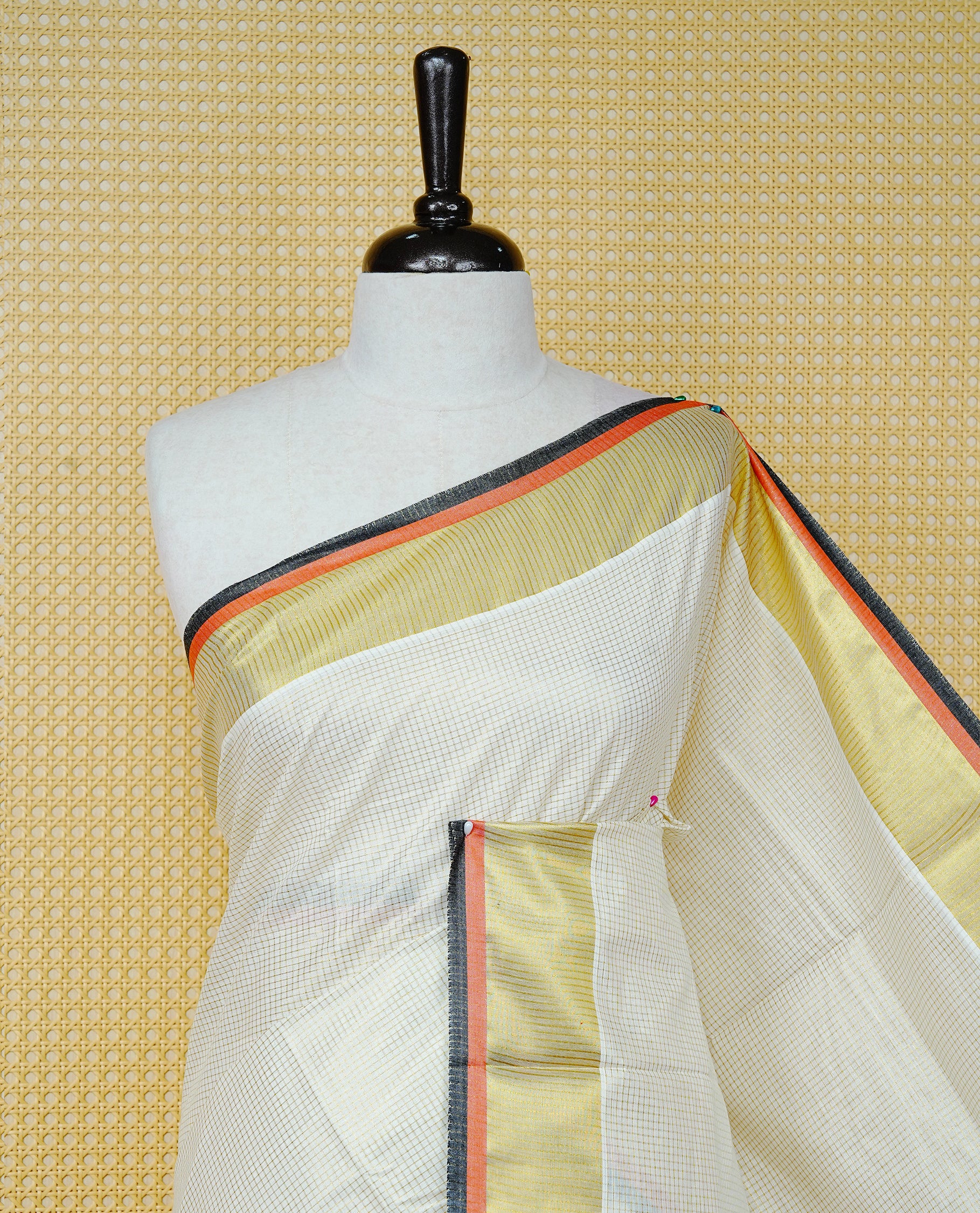 Cream colour cotton Kerala saree Featuring Gold zari Checks across the body, complemented by Classy gold zari with an orange & black Border & pallu, paired with a matching blouse piece.