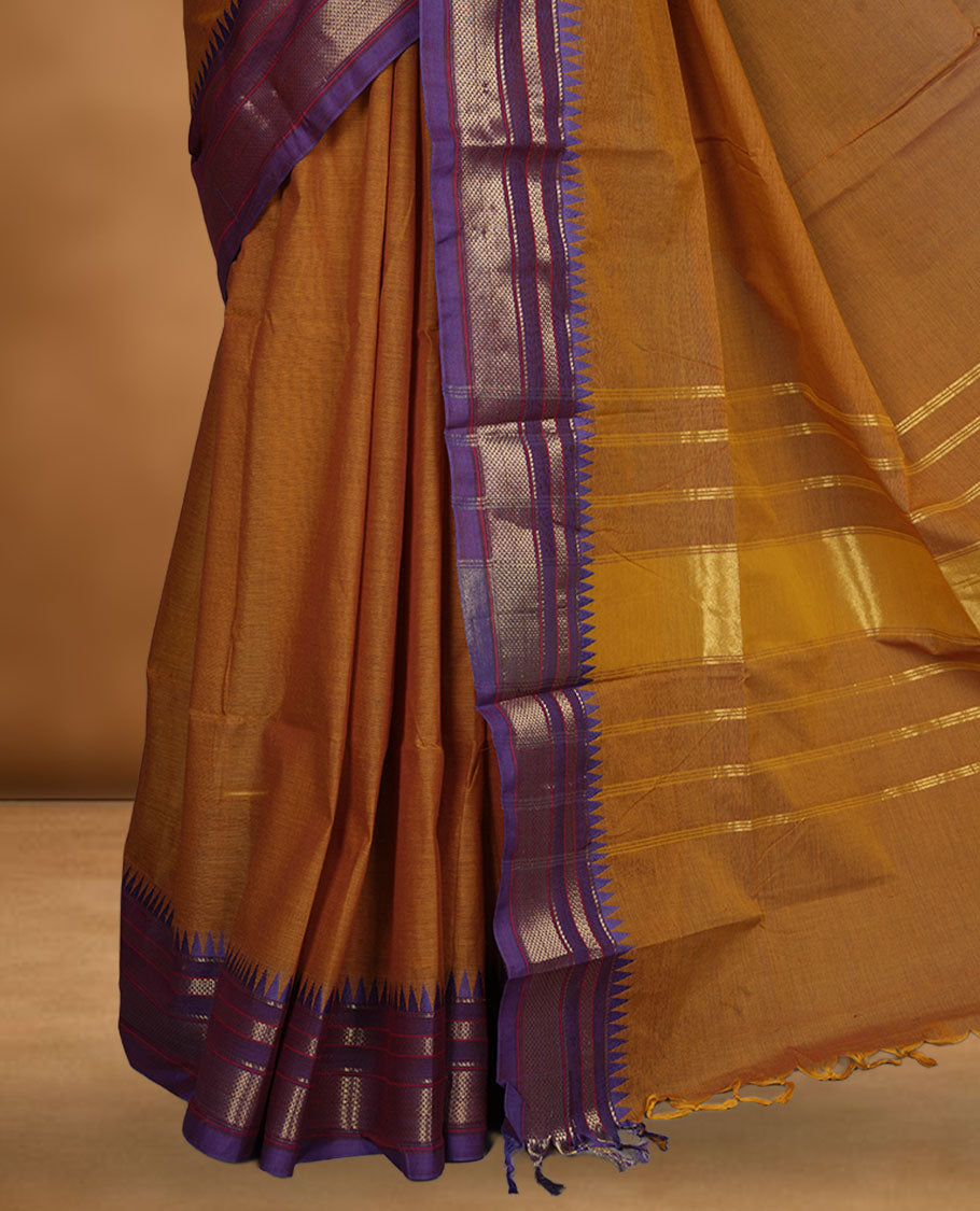 Brown colour chettinad cotton saree featuring elegant plain body highlighting contrast indigo colour with gold zari traditional border, pallu and paired with matching blouse piece.