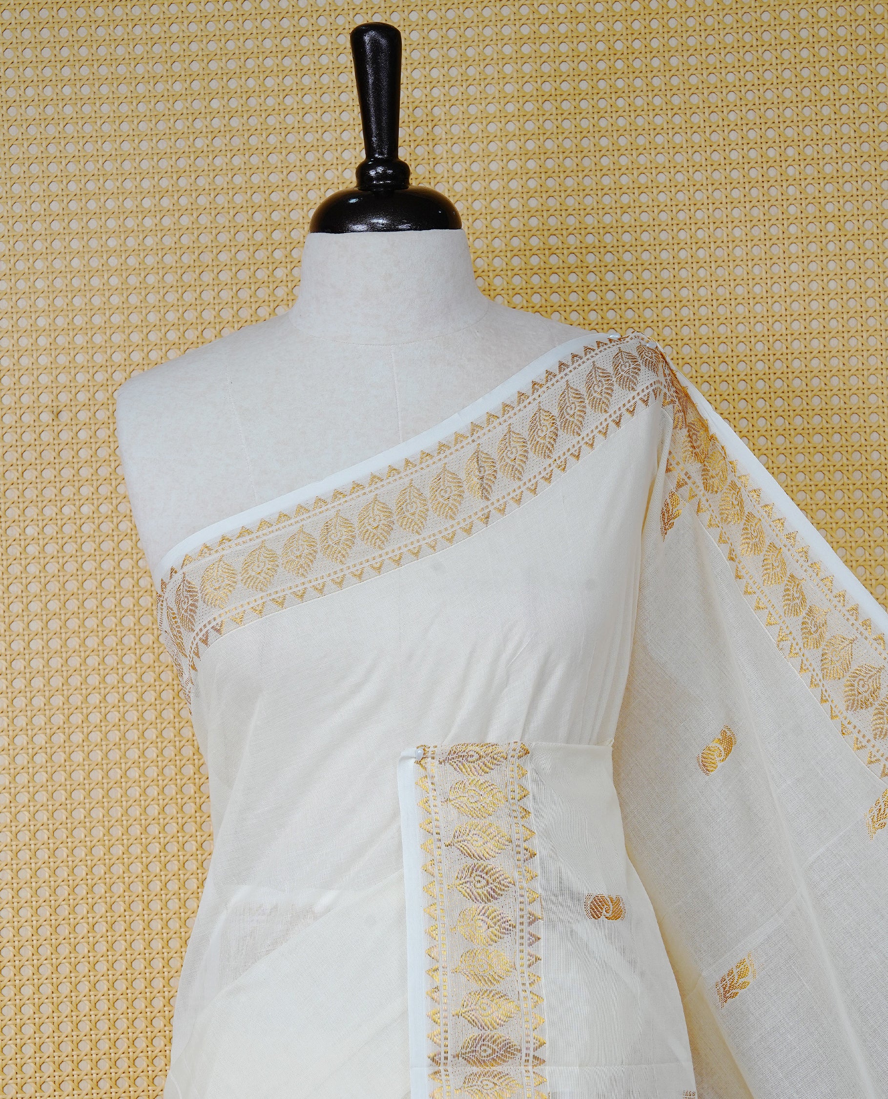 Cream Colour Cotton Kerala Saree Featuring Gold Buttas on the Body, a Classy Gold Zari Border, and a Traditional Black Colour Lord Krishna Thread work and Gold Zari Pallu, Paired with a Matching Blouse Piece.