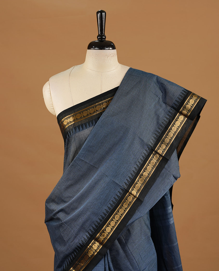 Bluish grey colour chettinad cotton saree featuring elegant plain body, complemented by black colour with zari border, paired with matching blouse piece.