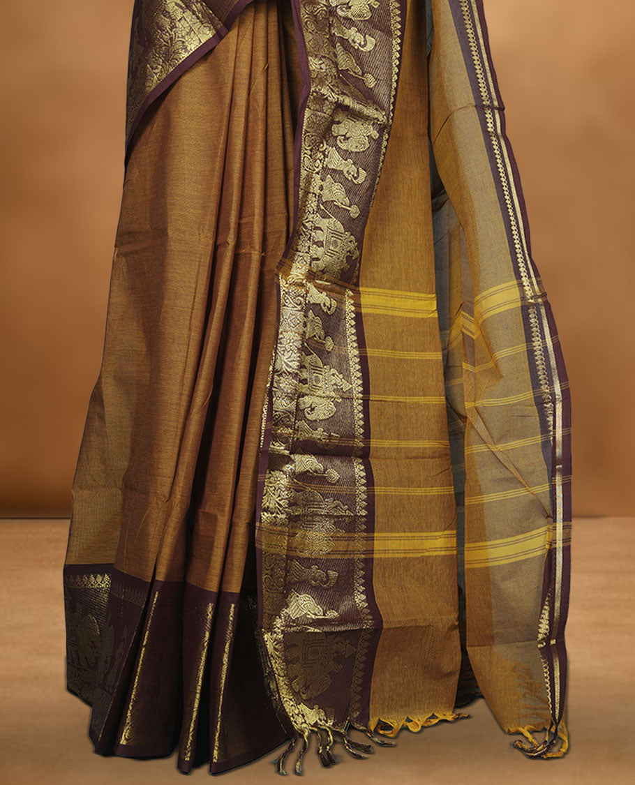 Mustard colour chettinad cotton saree featuring plain body, contrast chocolate brown colour with traditional gold zari border paired with matching blouse.