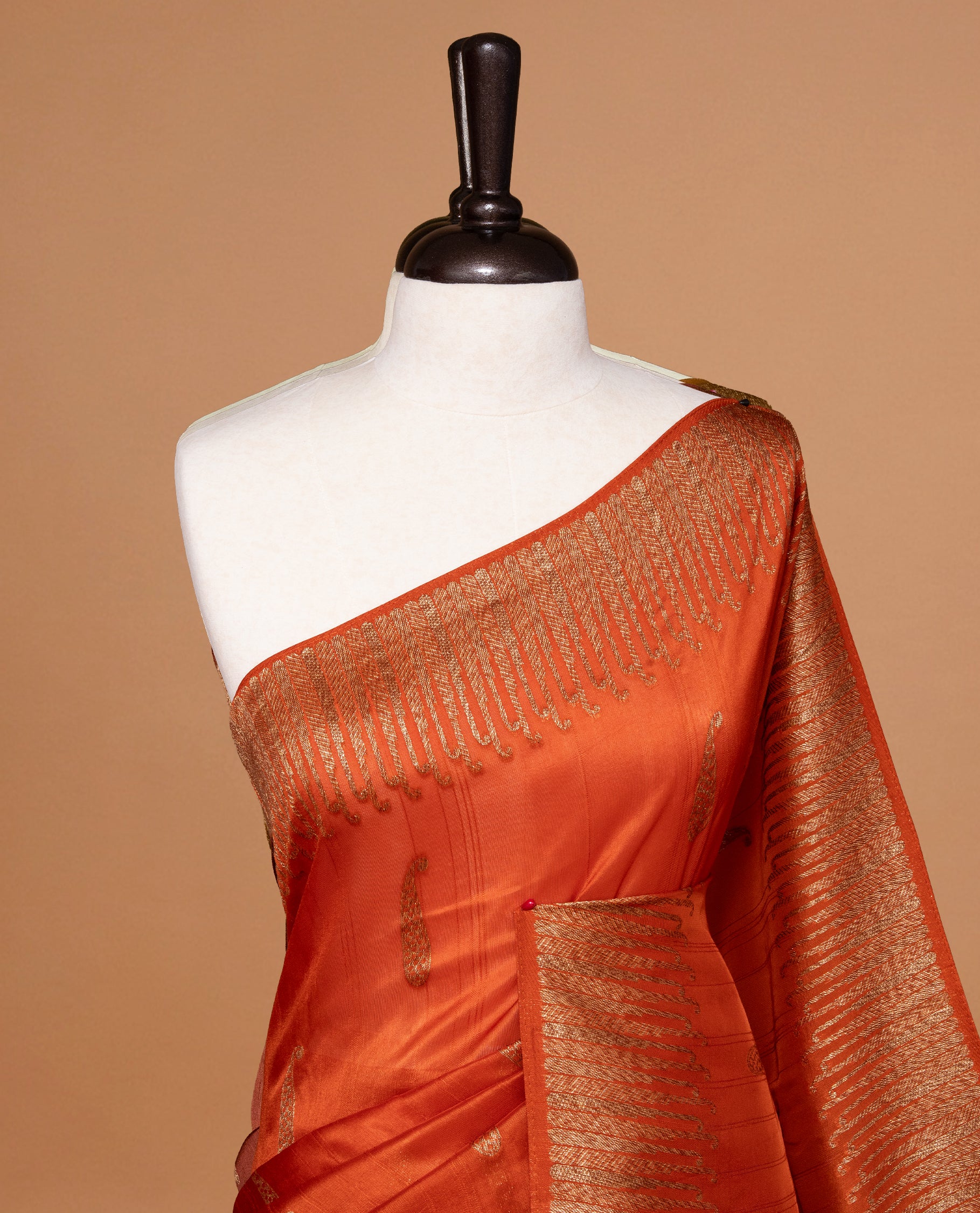 Burnt Orange colour Semi Banaras Tussar Georgette Featuring Gold zari Leaf pattern on body, Finished with Gold zari border and paired with matching blouse piece.