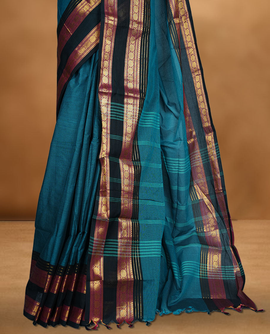 Teal colour chettinad cotton saree featuring plain body, contrast black and red colour with traditional gold zari border paired with matching blouse.