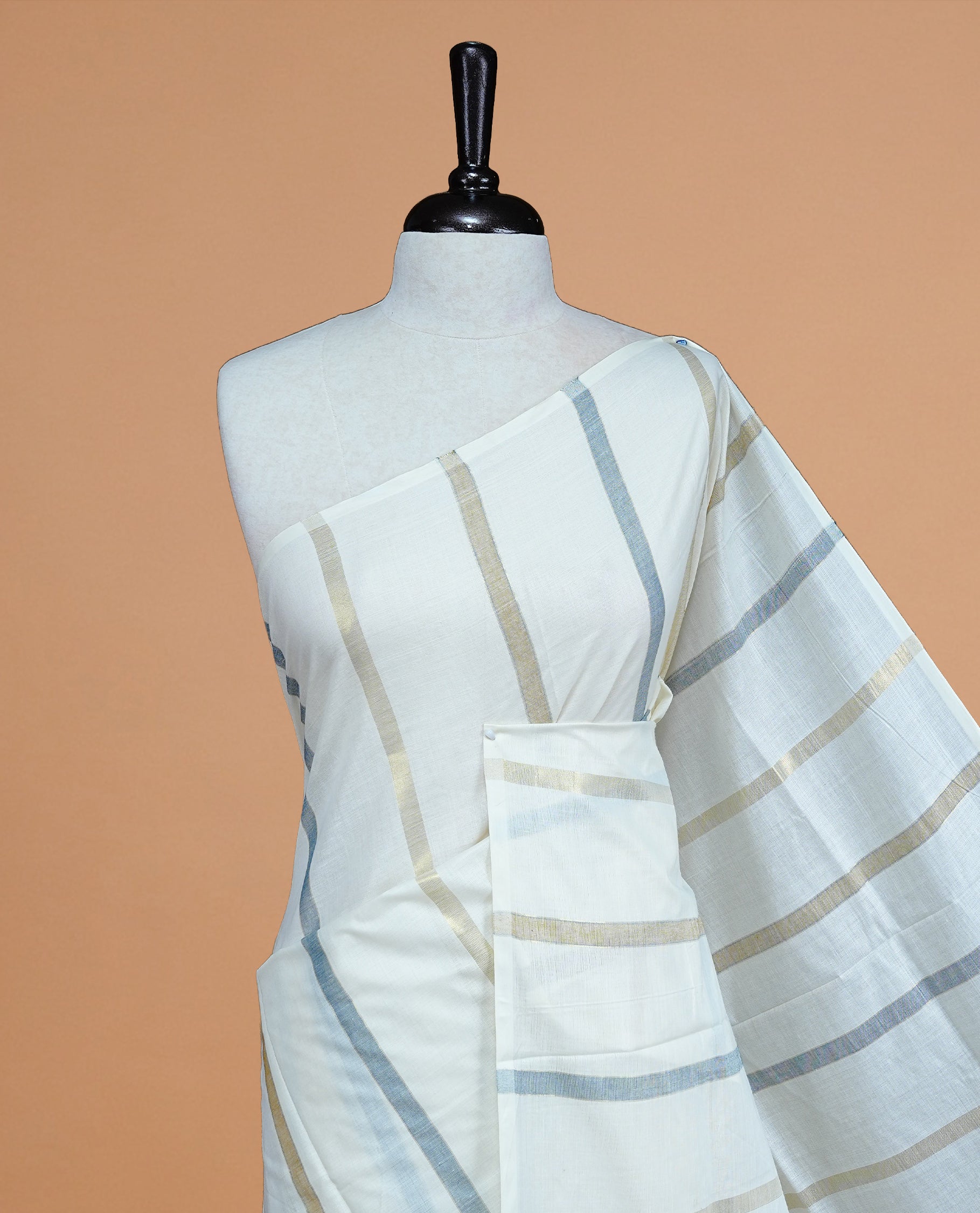 Cream Colour Cotton Kerala Saree Featuring Blue & Gold Zari Strips On The Body & Pallu, Paired With A Matching Blouse Piece.