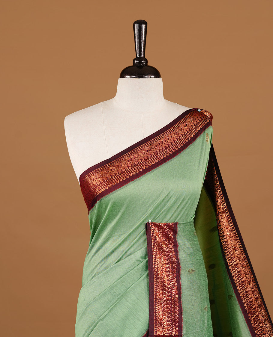 Pista green colour kalyani cotton saree featuring gold zari motifs on body, highlighting contrast Maroon colour with Antique gold zari border, paired with matching blouse piece.