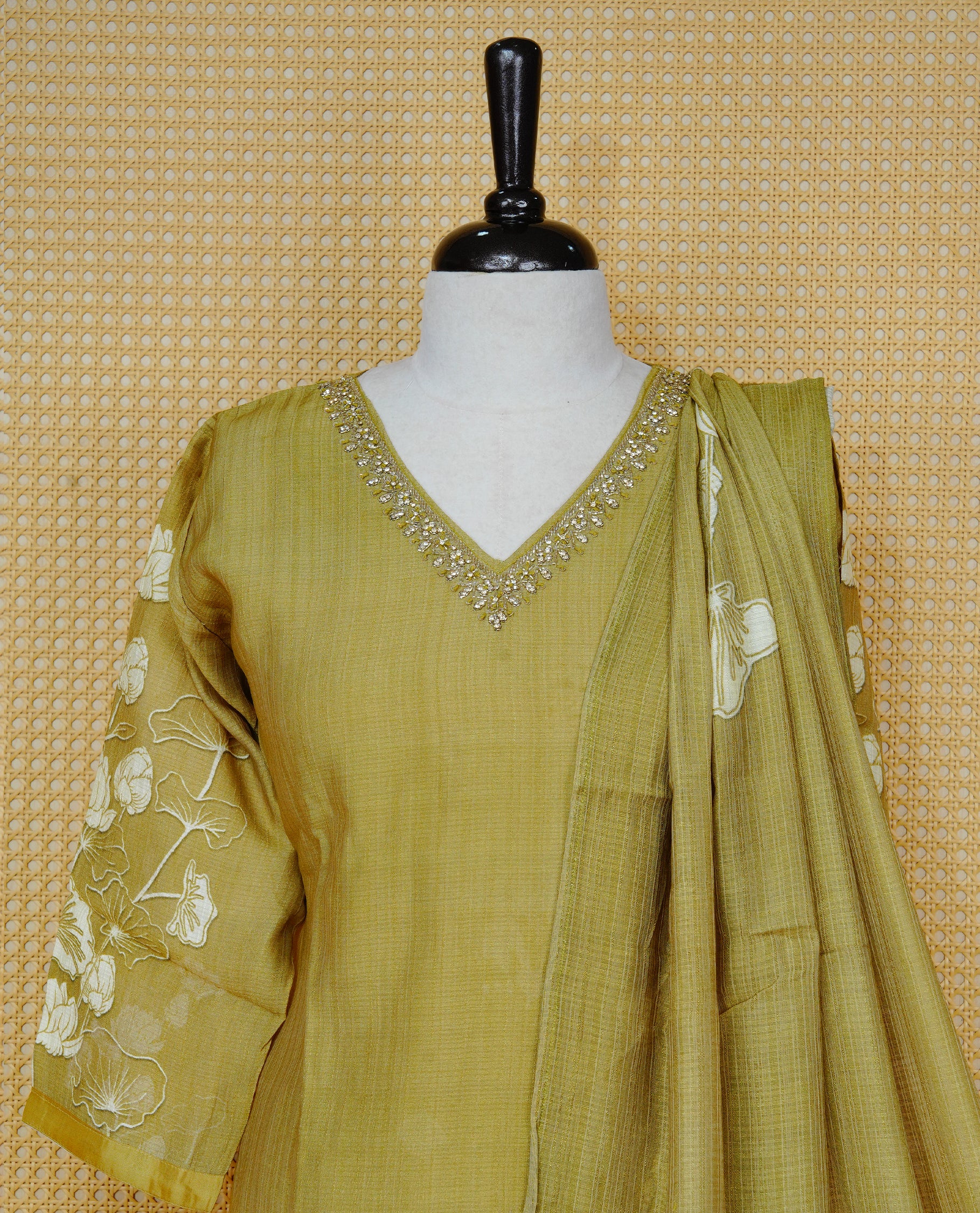 Olive green colour churidar set with a Stone & Bead Work on the V-neckline, floral printed sleeves , paired with a matching floral printed woven dupatta and solid pants.