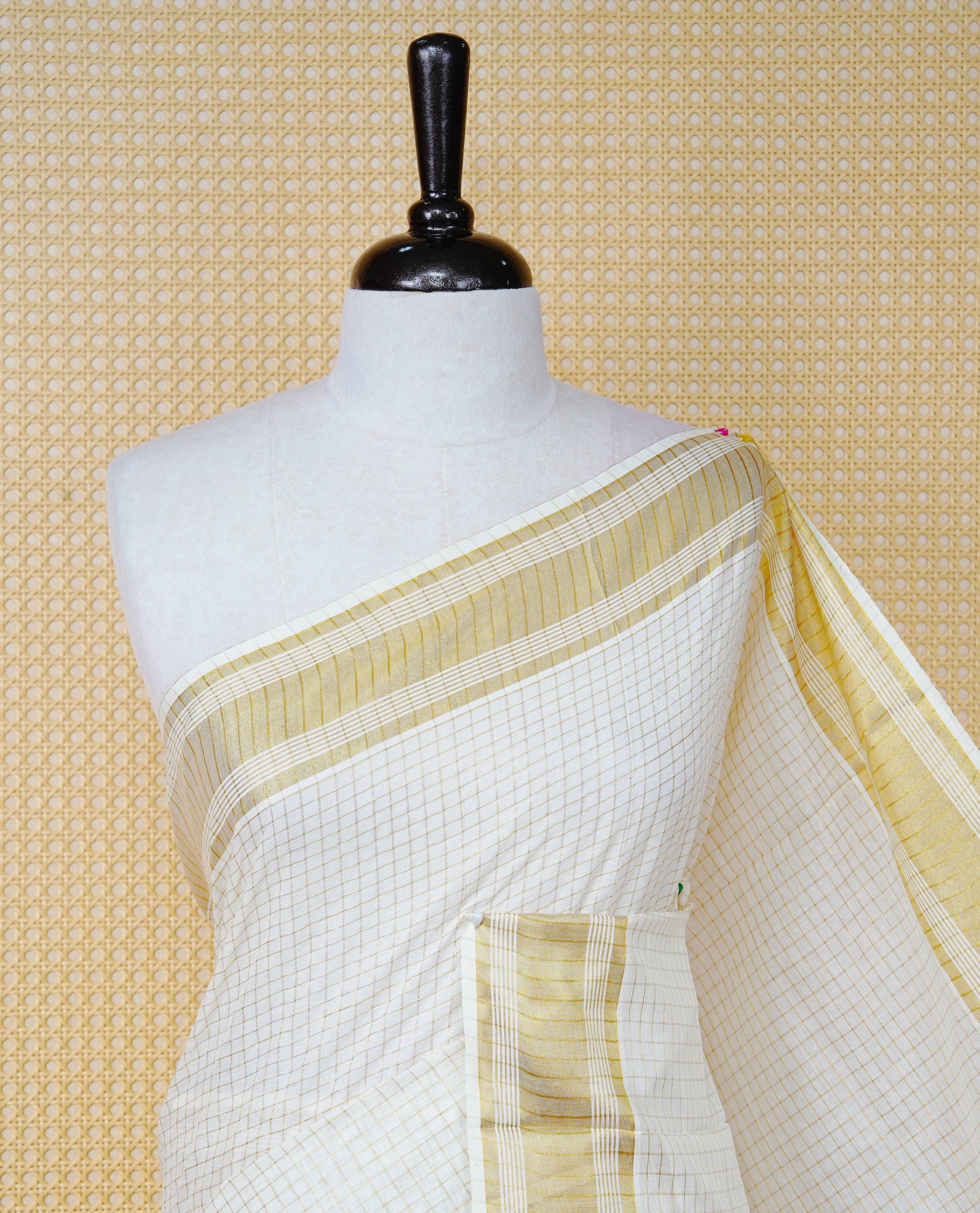 Cream colour Cotton kerala saree featuring Gold zari Checks on body, complemented by Gold zari border & Maroon with gold zari Pallu, paired with matching blouse piece.