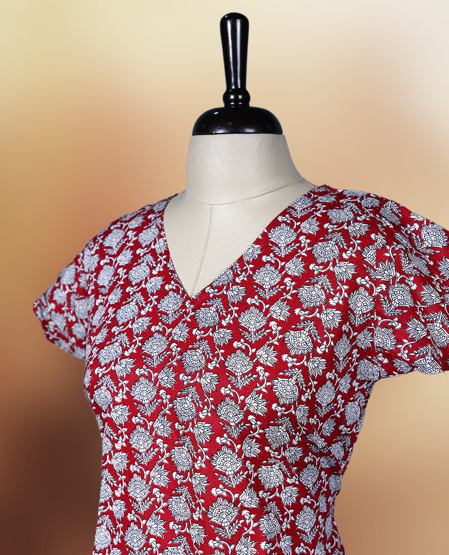 Red colour nightwear with a charming white floral print, featuring a V neckline, flutter sleeves, and a flared ruffle hem, A perfect pick for casual days, summer outings, or light festive wear.