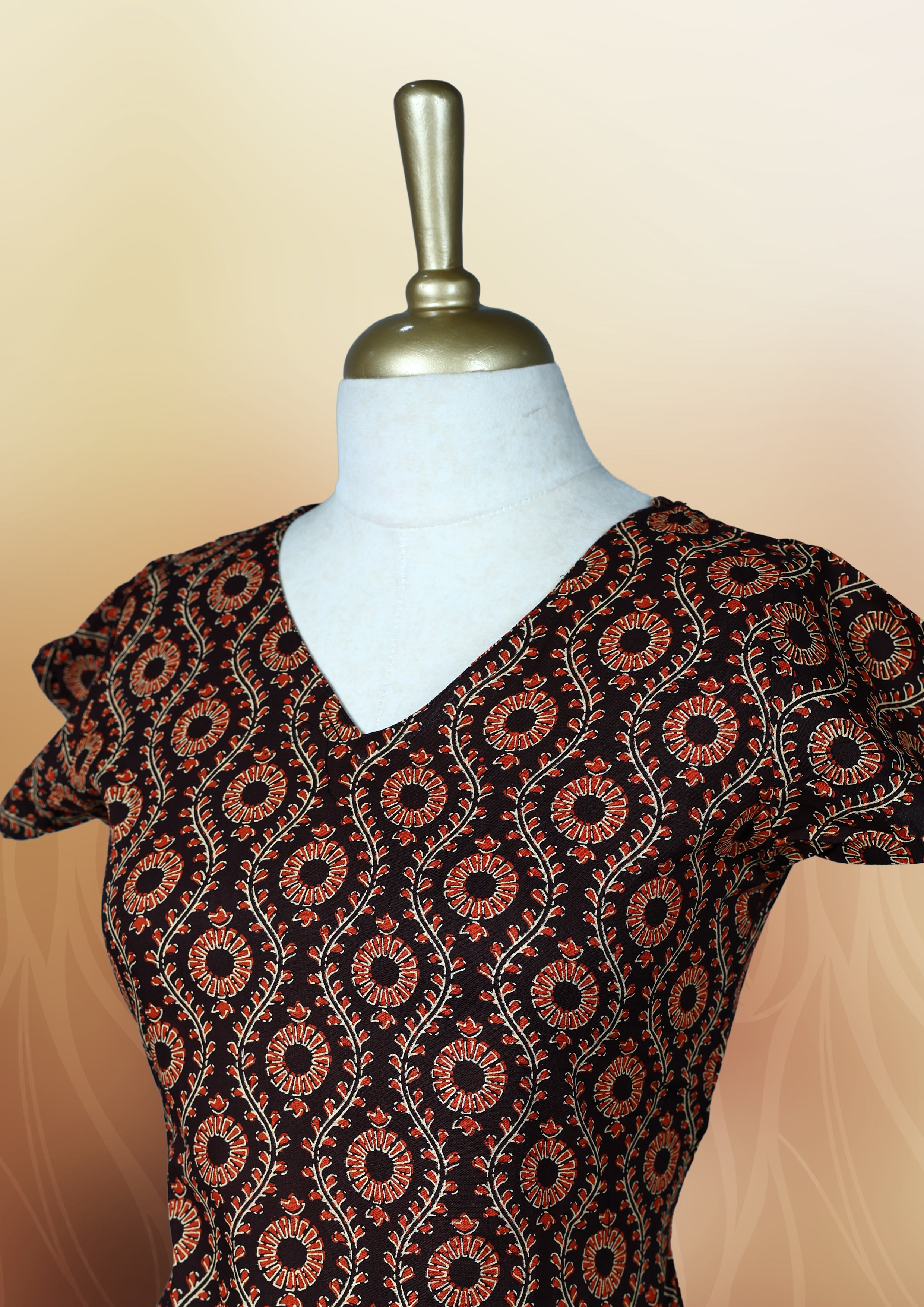Brownish black colour nightwear with an elegant red and beige ethnic print, Features a flattering V neck, short sleeves, and a flared hem, Ideal for casual outings, festive gatherings, or comfortable daily wear.