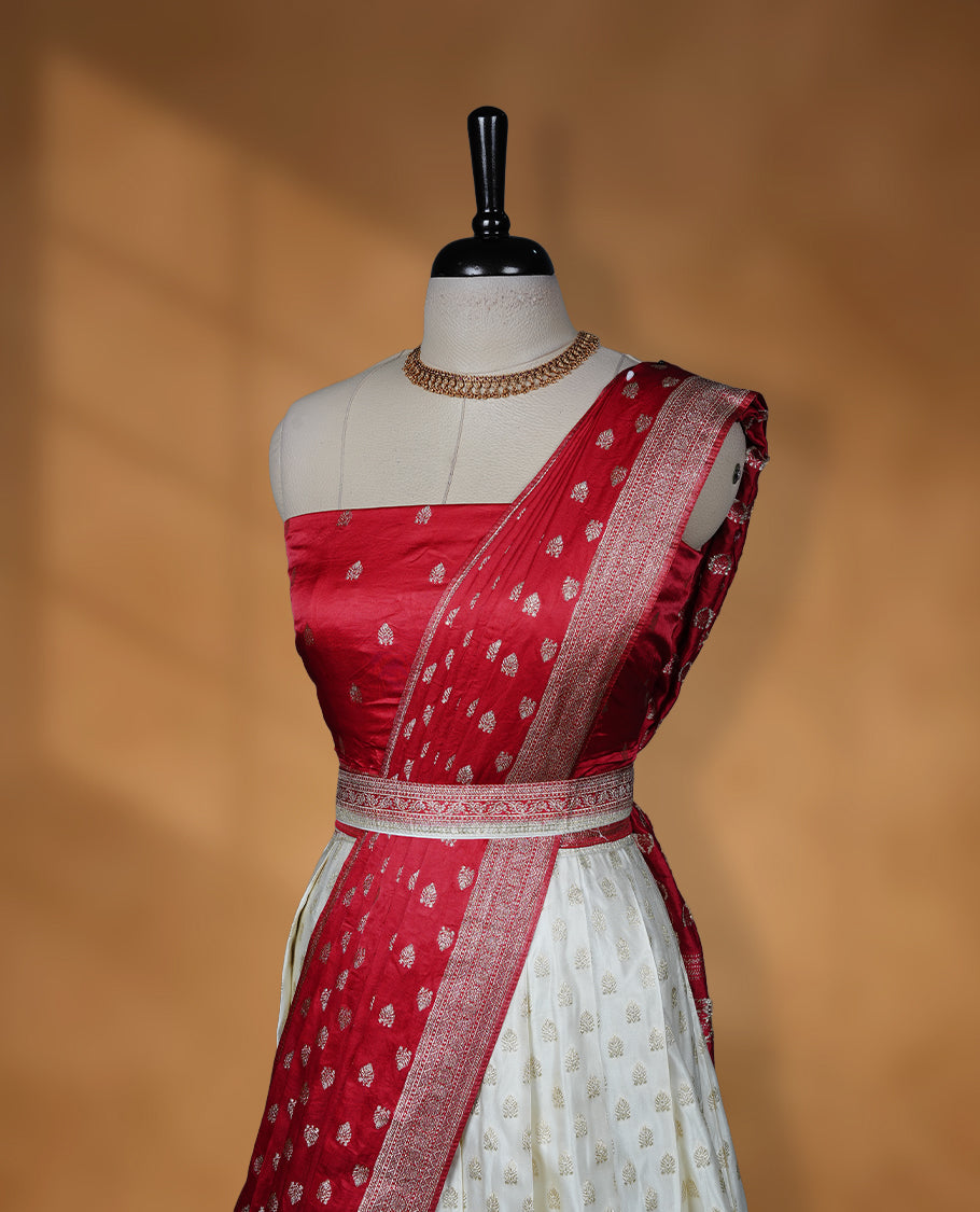 Off white semi banaras semi stitched dhavani set featuring gold zari motifs and contrast red colour and traditional border, unstitched gold zari blouse piece and matching Duptta.