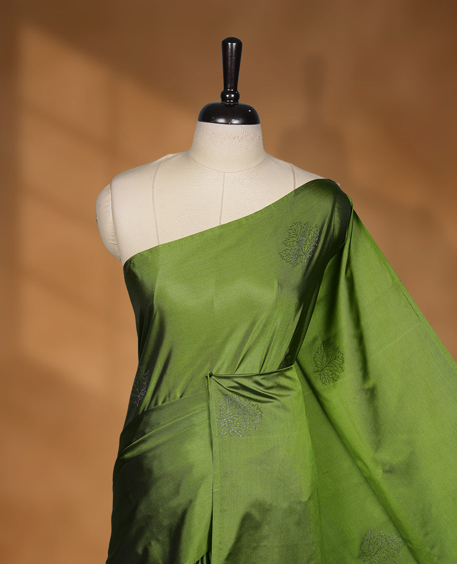 Olive green colour soft silk saree featuring Antique zari motifs on body with Highlighting contrast Navy blue colour pallu and paired with matching blouse piece.