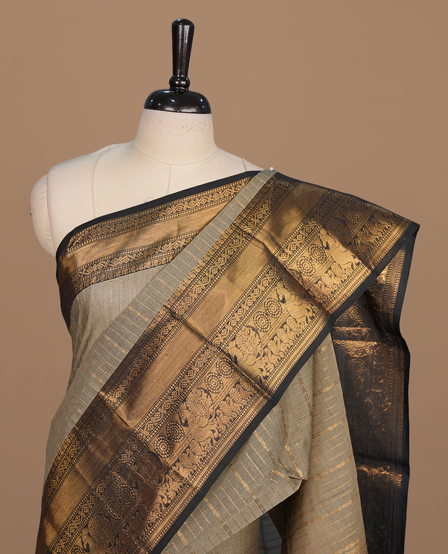 Grey colour chettinad cotton saree featuring gold zari stripes on body, complemented by contrast black colour with gold zari border, paired with matching blouse piece.