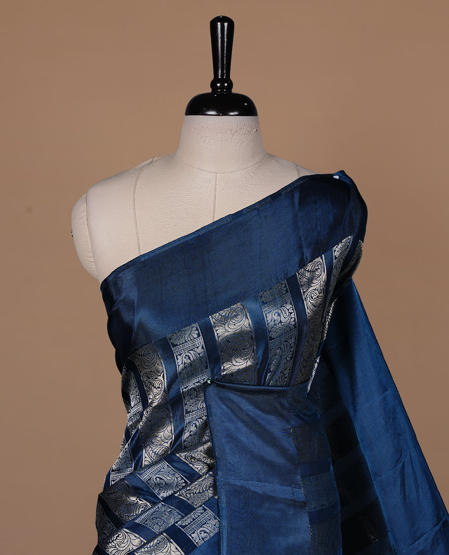 Teal colour banaras crepe saree featuring gold & silver zari design stripes on body, complemented by self colour border, paired with matching blouse piece.