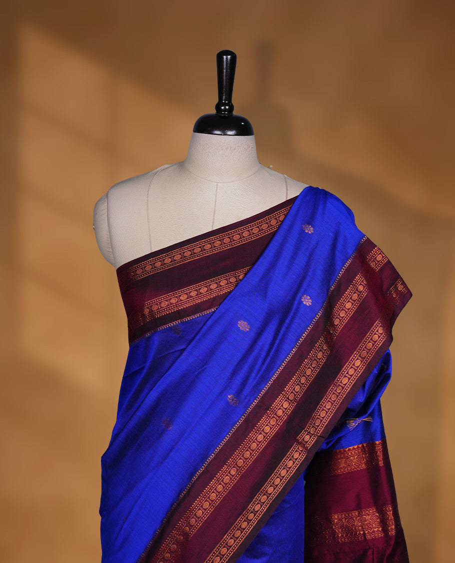 Royal blue colour saree with subtle zari motifs, complemented by a rich maroon zari border and traditional pallu, paired with a matching blouse.
