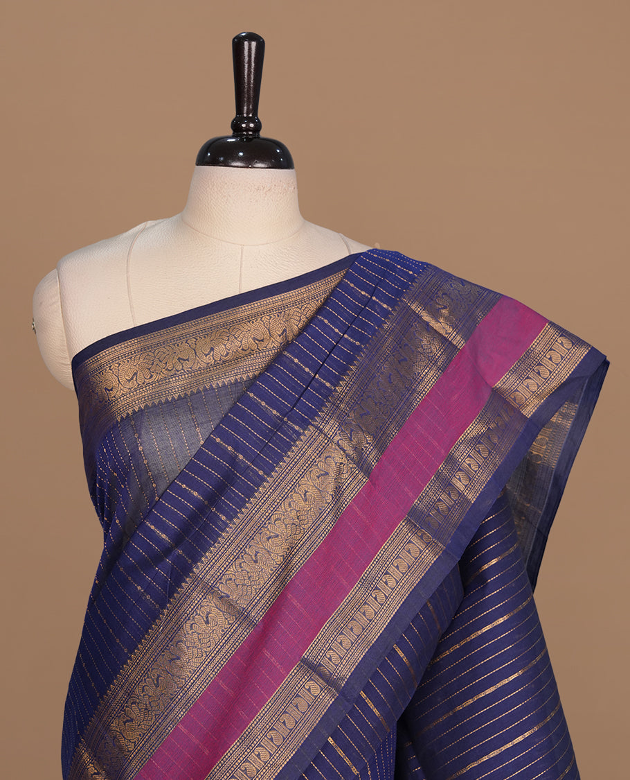 Navy blue colour chettinad cotton saree featuring gold zari stripes on body, complemented by magenta with gold zari border, paired with matching blouse piece.