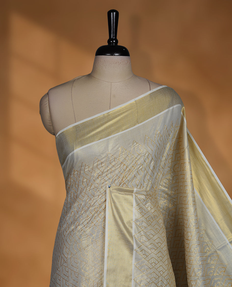 Off white colour Tissue Kerala saree featuring an elegant all-over zari patterned body, complemented by a rich golden zari border and traditional pallu, paired with a matching blouse.