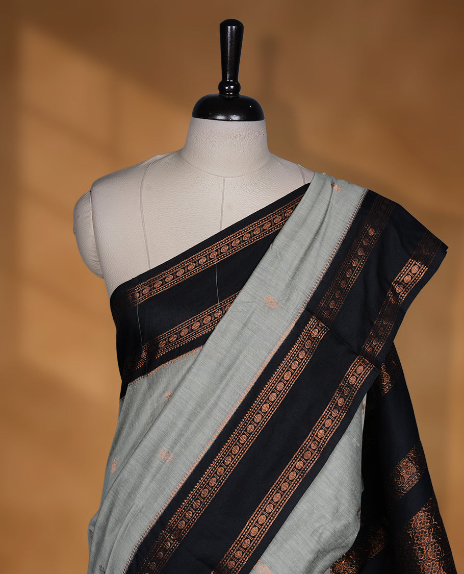 Grey colour Kalyani cotton saree featuring a plain elegant body, complemented by a black zari border and traditional woven pallu, paired with a matching blouse.