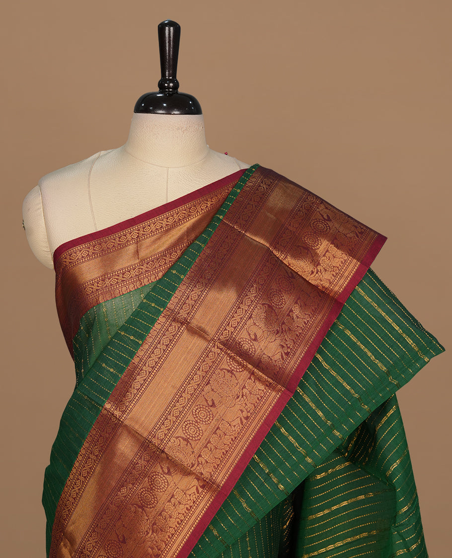 Green colour chettinad saree featuring gold zari stripes on body, complemented by contrast maroon colour with traditional border, paired with matching blouse piece.