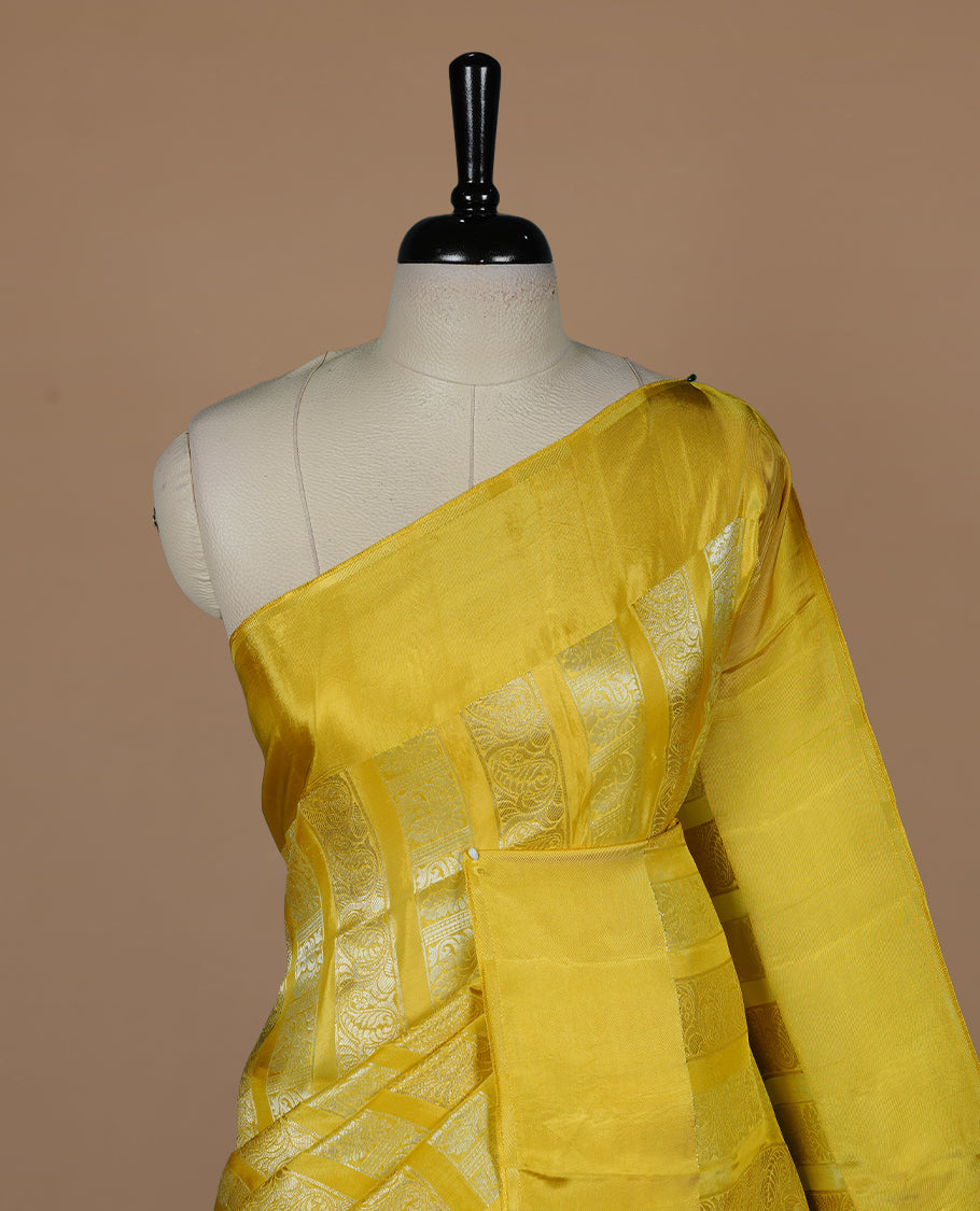 Yellow colour banaras crepe saree featuring gold & silver zari design stripes on body, complemented by self colour border, paired with matching blouse piece.