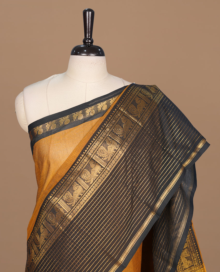 Mustard colour chettinad cotton saree featuring elegant plain body, complemented by contrast black colour with traditional border, paired with matching blouse piece.
