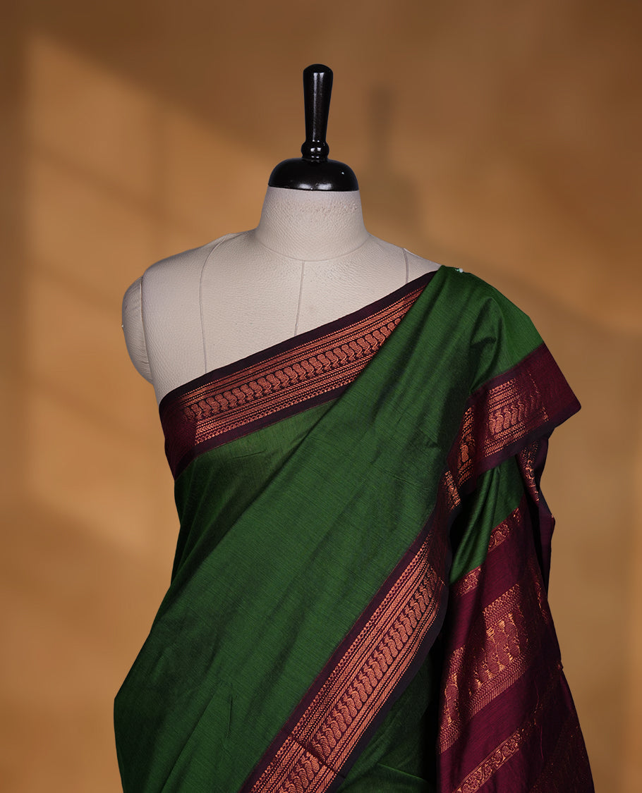 Green colour Kalyani cotton saree featuring a plain elegant body, complemented by a deep maroon border and traditional woven pallu, paired with a matching blouse.