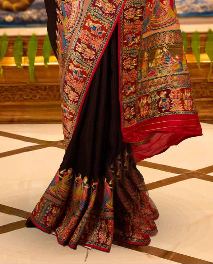 Black colour Pashmina silk saree exquisitely woven with vibrant mythological and architectural motifs across the body, bordered by elaborate narrative scenes and a grand artistic pallu, paired with a matching woven border blouse piece.