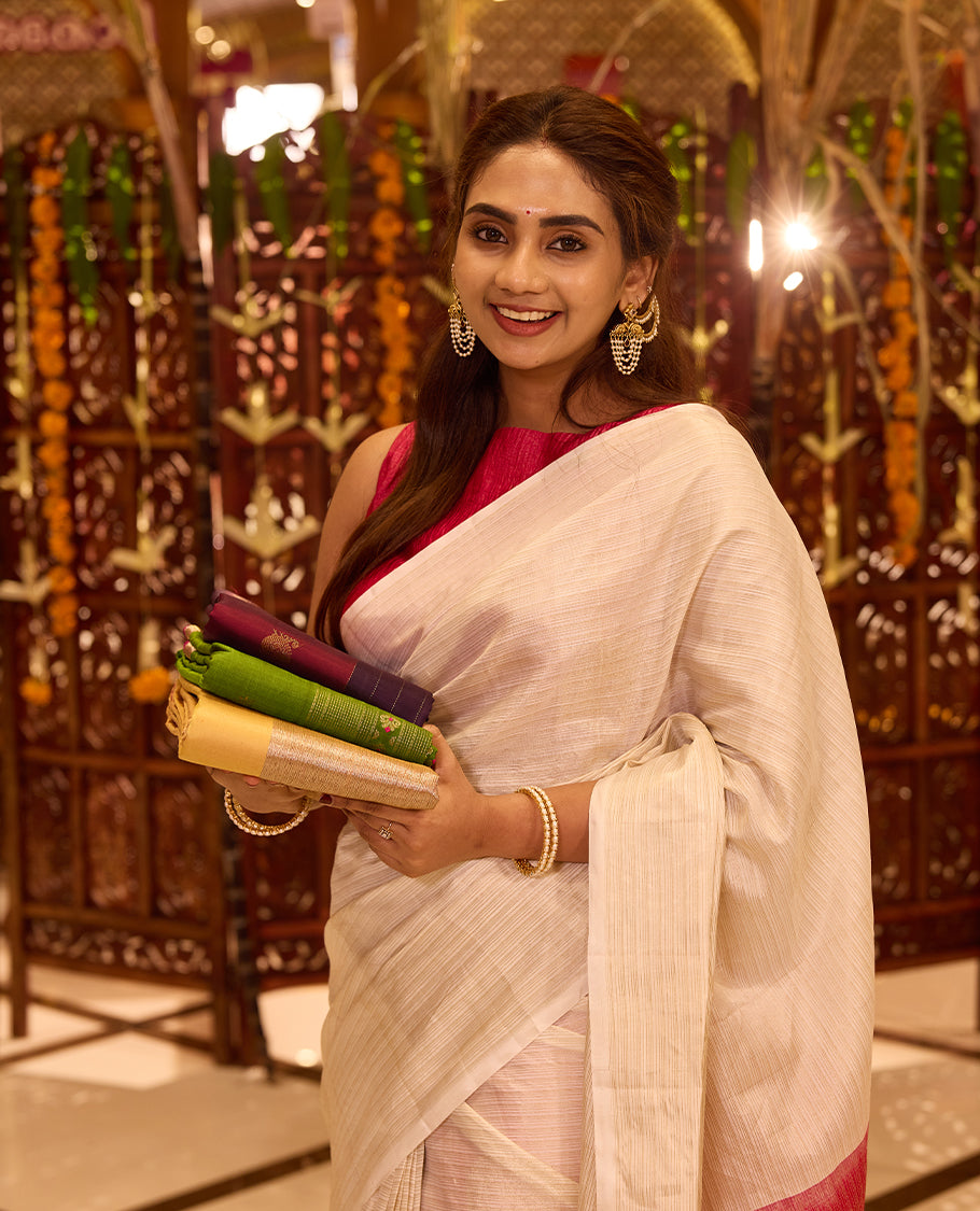 Elegant Ivory colour Kancheepuram silk saree enriched with a subtle sheen, gracefully contrasted by a bold Rani Pink pallu that adds a festive touch, styled with a matching blouse