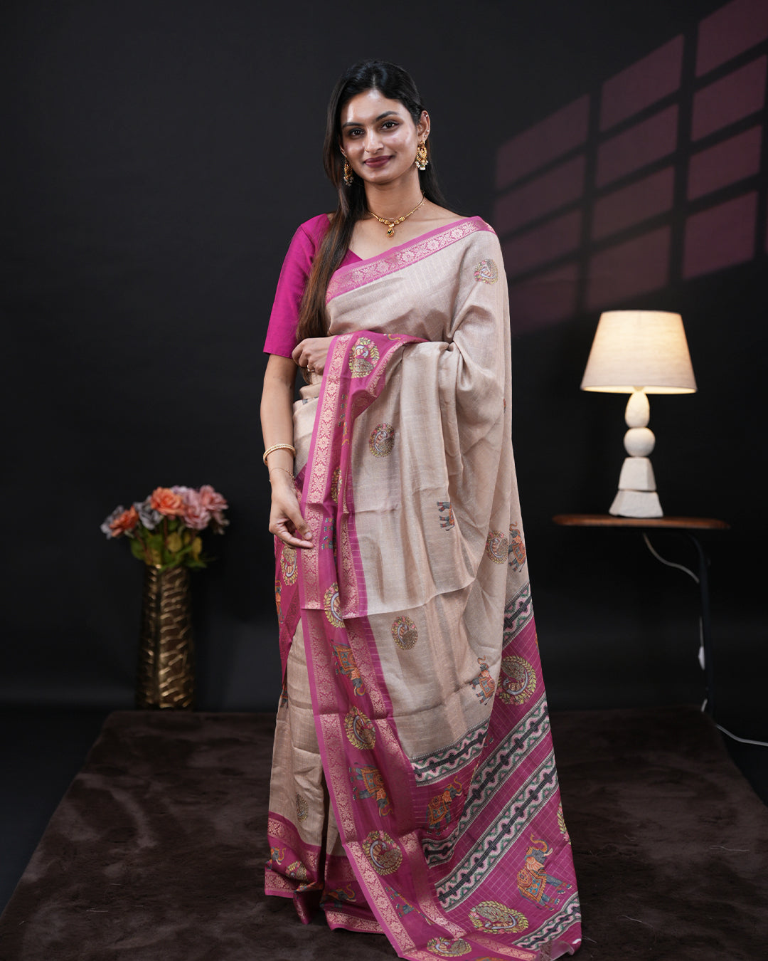 Cream Colour Moss chiffon saree featuring gold zari checks with elephant & peacock prints on the body, Pink Colour double border with elephant prints and a contrast designed pallu, paired with a contrast designed blouse piece.