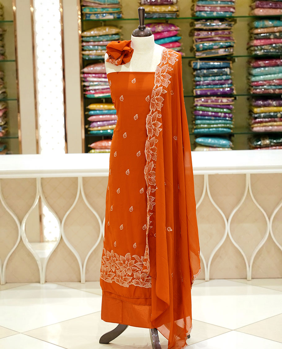 Burnt orange colour georgette salwar set featuring gold zari buttas on body, floral embroidery and scalp work on dupatta, paired with matching bottom.