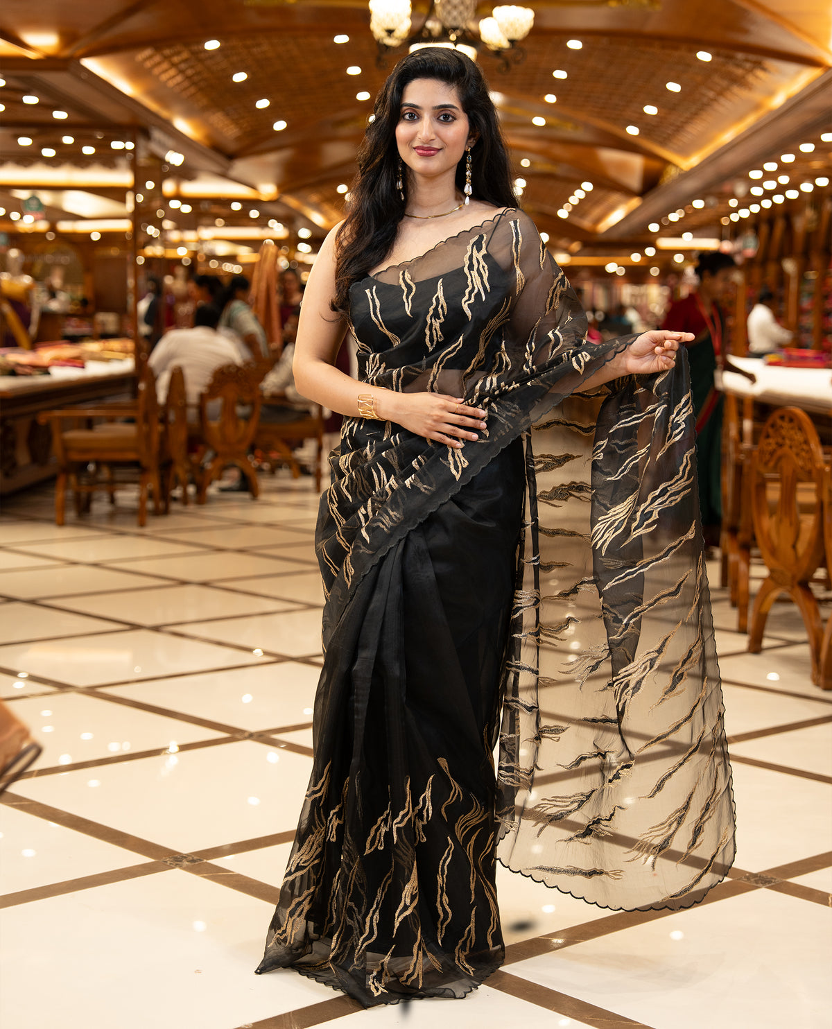 Black colour sheer Organza saree featuring Gold thread embroidery with modern wavy & flame inspired motifs and scallop border, comes with matching organza blouse.