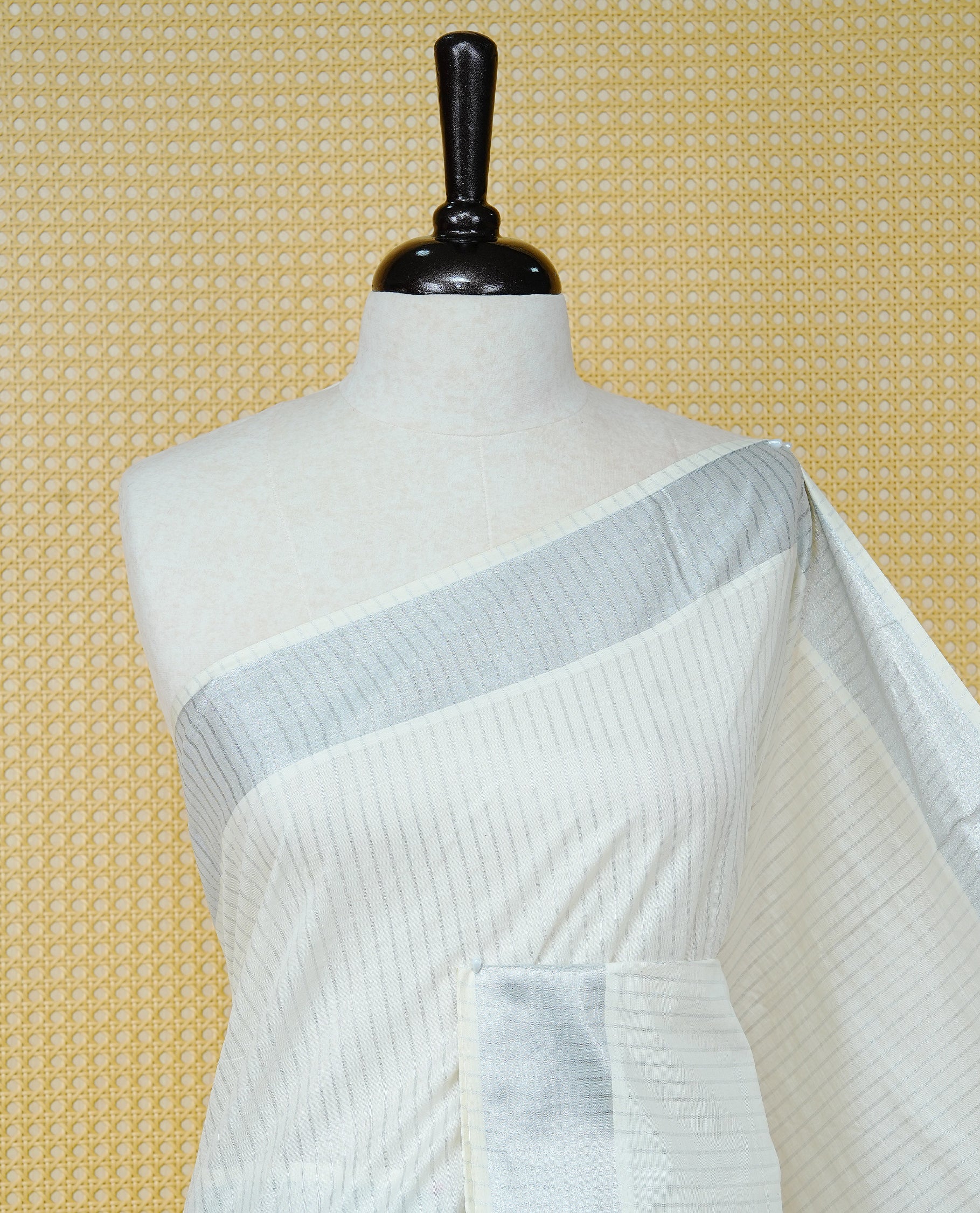 Cream colour Cotton kerala saree featuring Silver zari Stripes on body, complemented by Silver Zari Border & Rose gold zari Pallu, paired with matching blouse piece.