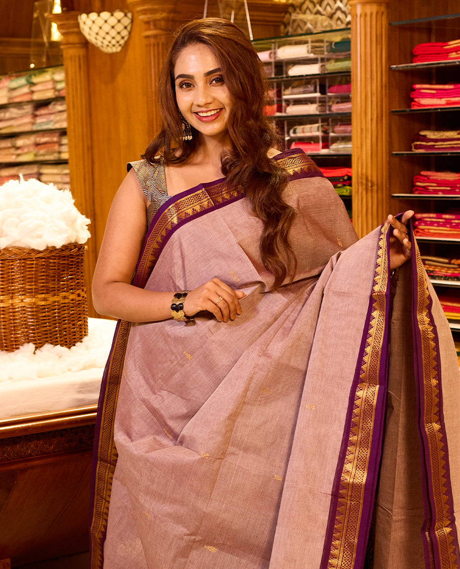 Muted rose pink colour chettinad cotton saree featuring subtle gold butta motifs on the body, highlighted with a rich purple contrast border and pallu accented in gold zari, paired with a matching blouse piece.