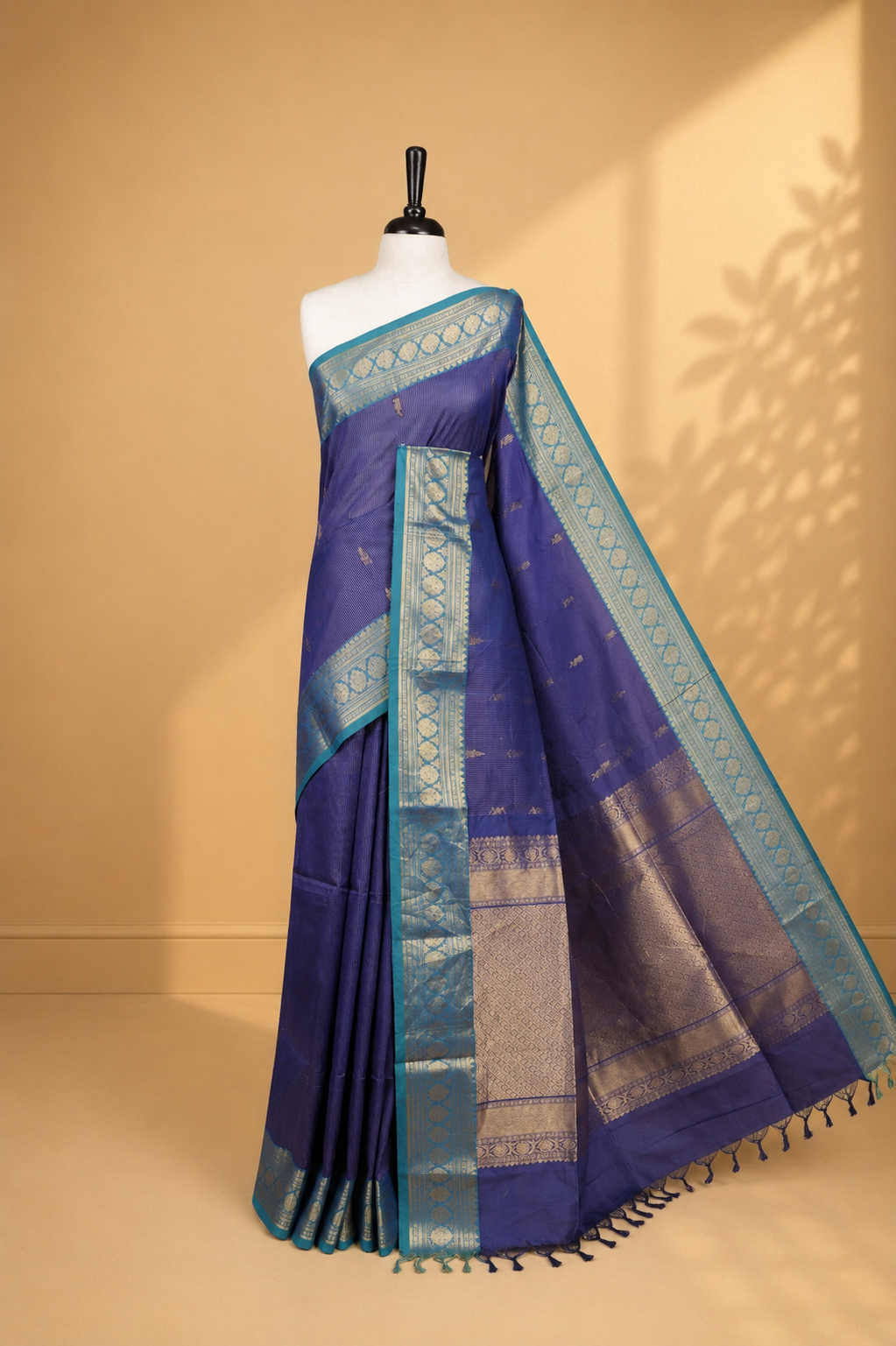 Navy blue colour chettinad cotton saree featuring gold zari stripes & motifs on body, complemented by Contrast Teal colour with zari border, paired with matching blouse piece.
