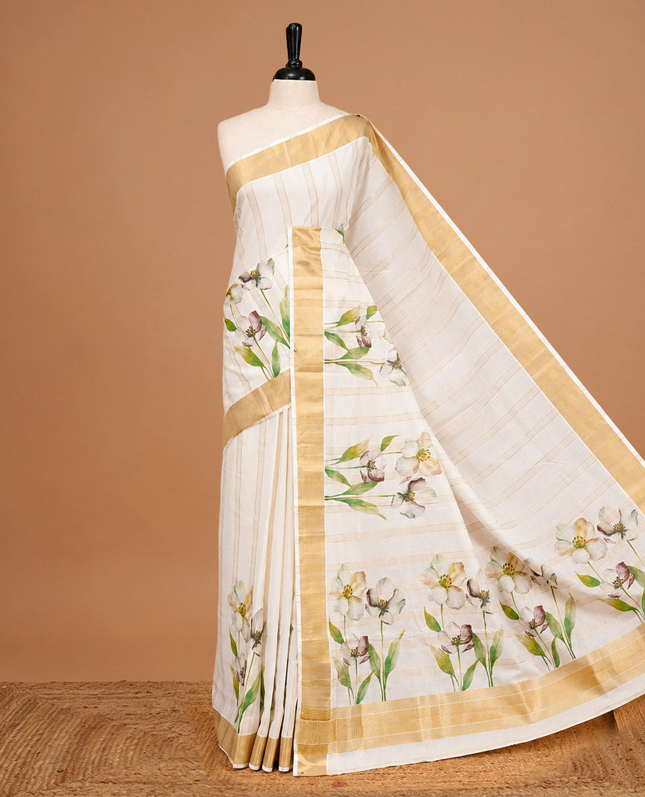 Cream Colour Cotton Kerala Saree Featuring Gold Zari Strips & Floral Printed Body, Enriched By A Light Gold Zari Border, Paired With A Matching Blouse Piece.