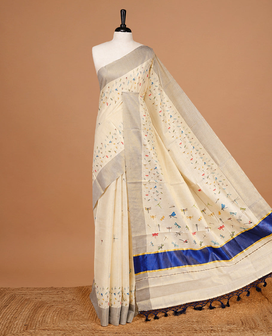 Cream Colour Tissue Kerala Saree Featuring Plain Body ,Complemented By Blue Zari With Dragonfly Printed Border ,Enhance By A Blue With Gold Zari Pallu ,Paired With A Matching Blouse Piece.
