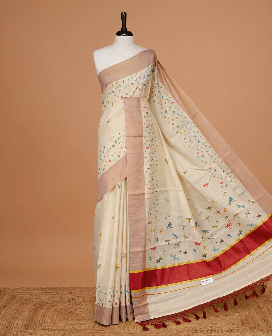 Cream Colour Tissue Kerala Saree Featuring Plain Body ,Complemented By Red Zari With Dragonfly Printed Border ,Enhance By A Red With Gold Zari Pallu ,Paired With A Matching Blouse Piece.