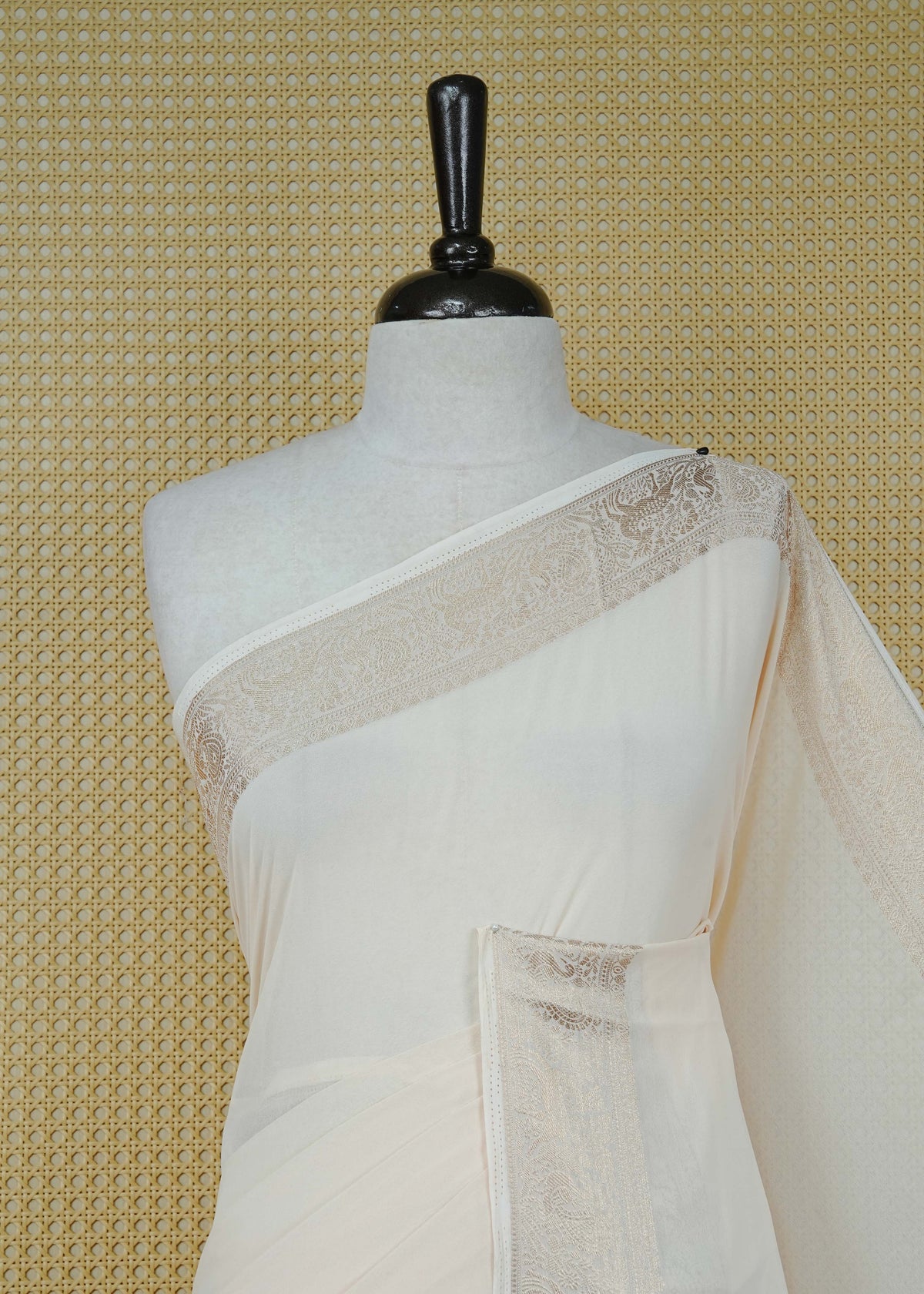 Cream colour georgette saree having plain body, peacock & deer gold zari detailed border, comes with matching blouse piece