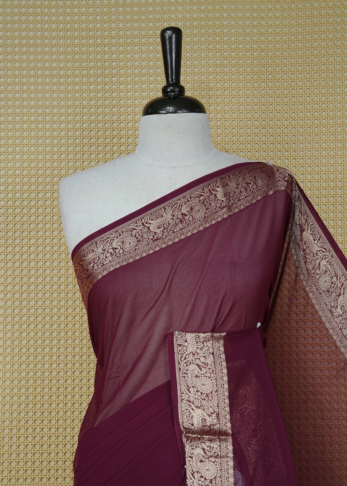 Wine colour georgette saree having plain body, peacock & deer gold zari detailed border, comes with matching blouse piece